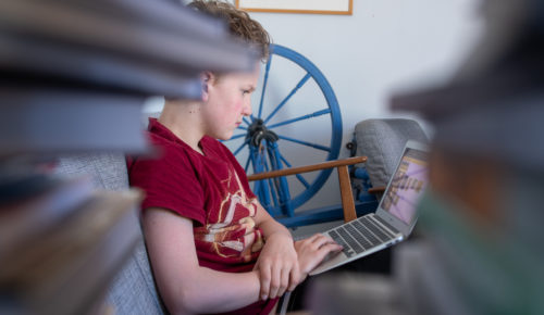 pojke sitter i soffan och arbetar på en laptop