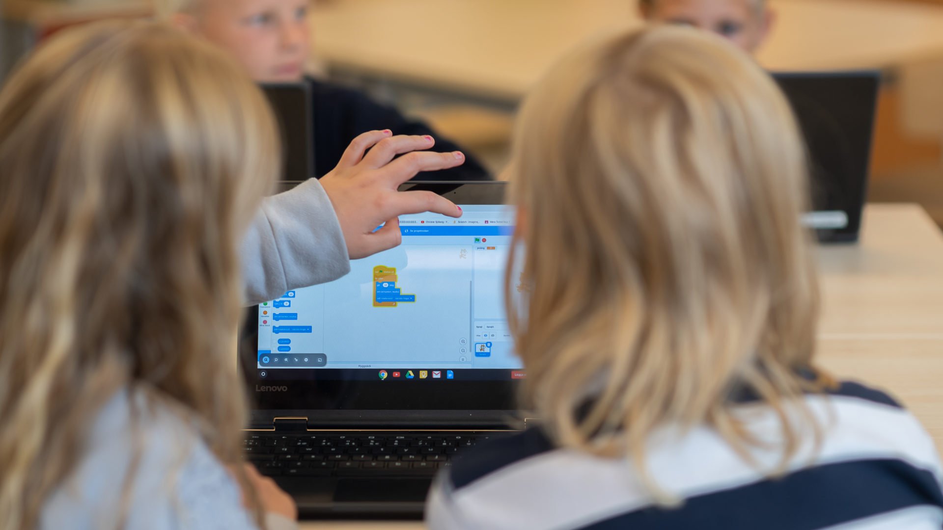 Elever arbetar med datorer i ett klassrum.