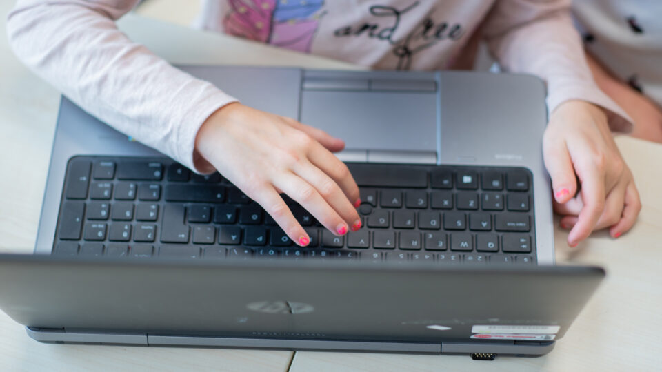 Barnhänder på tangentbordet på en laptop.