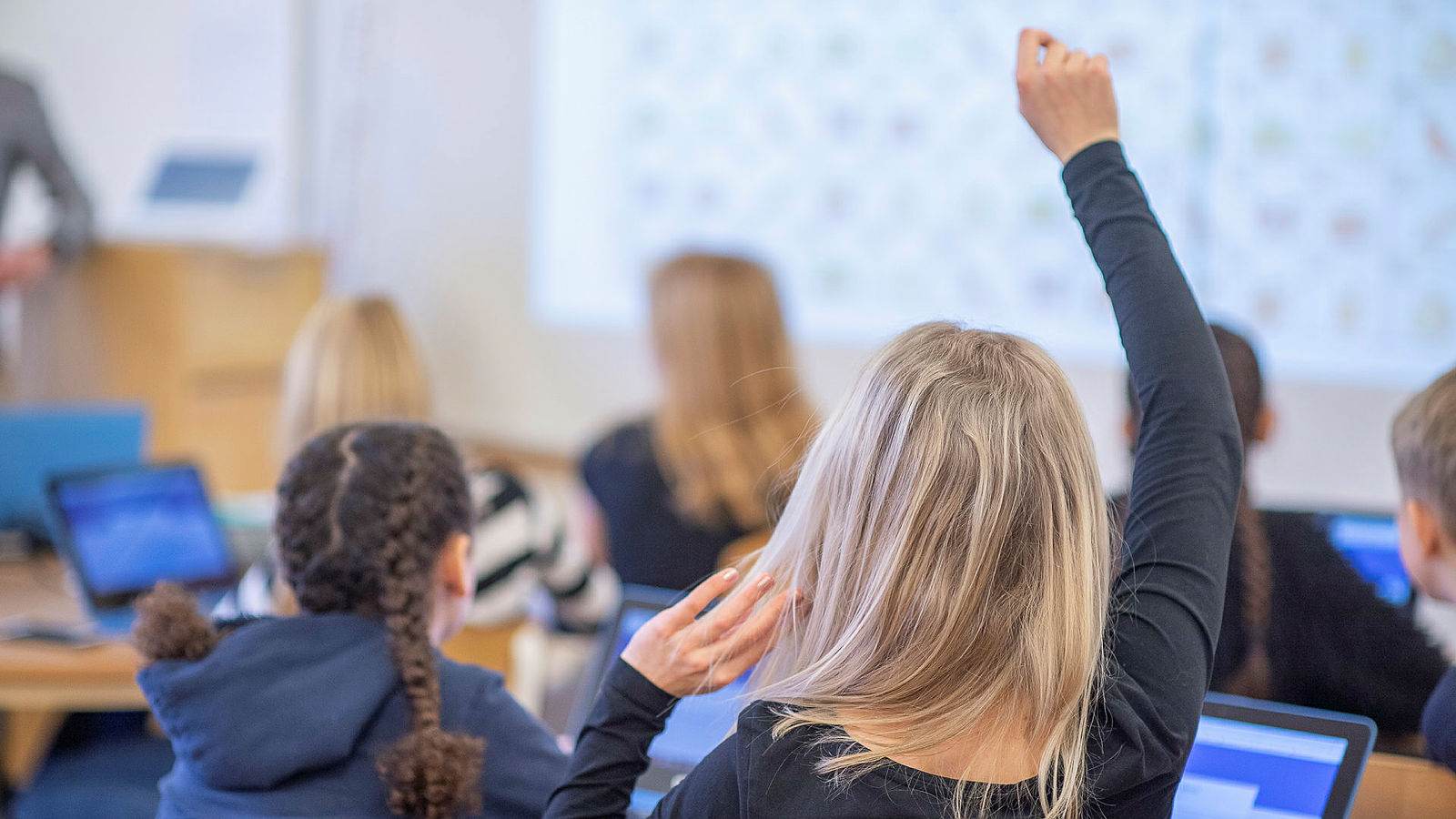 tjej räcker upp handen i klassrum