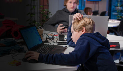 Ett barn sitter vid ett skrivbord och programmerar på sin laptop.