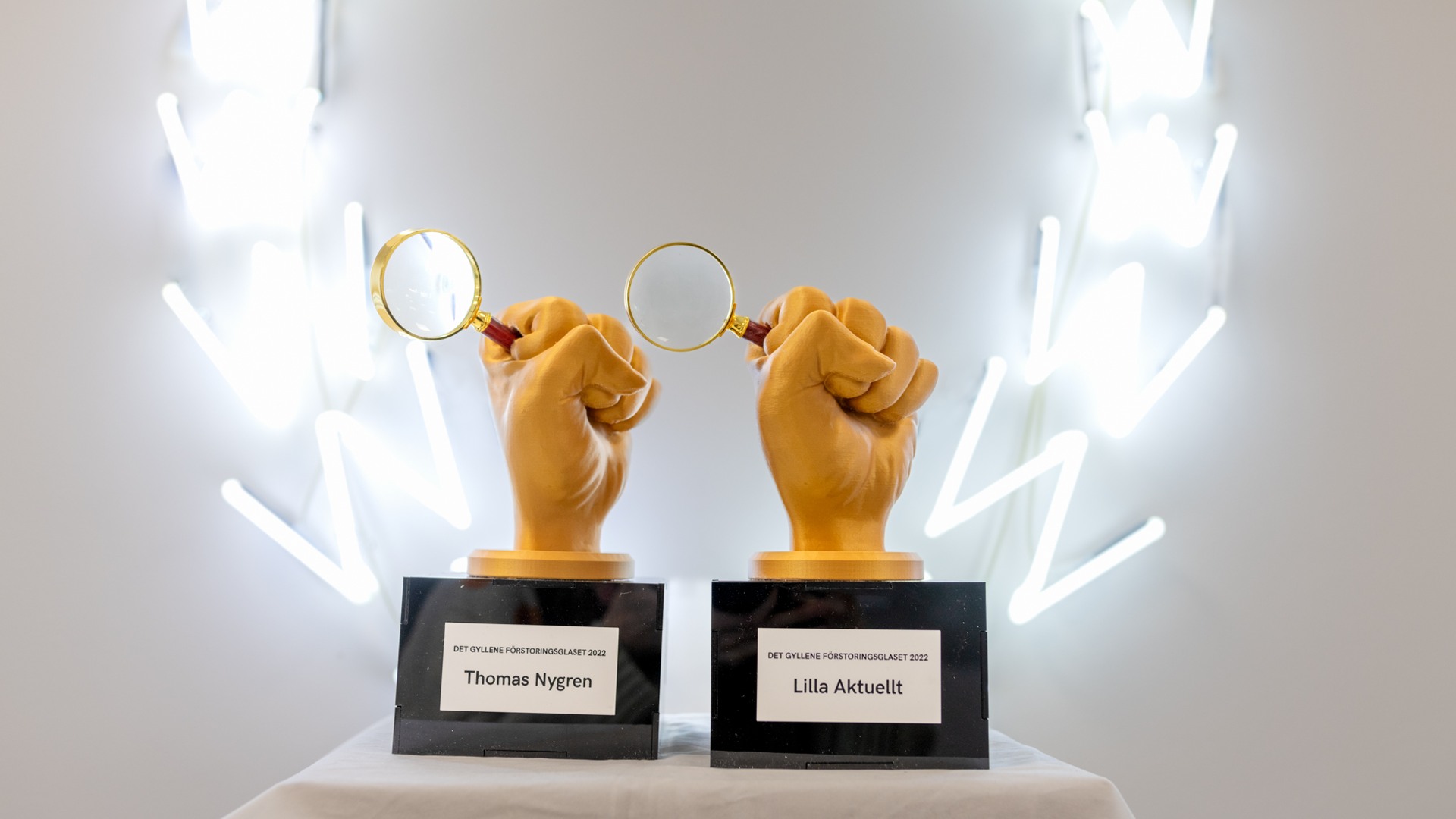 Ett par händer som håller i förstoringsglas på ett bord.